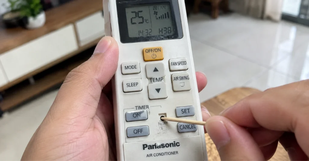 Dùng tăm nhấn nút reset trên remote máy lạnh Panasonic