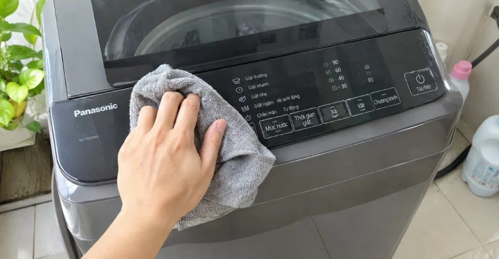 Dùng khăn khô lau sạch bề mặt bảng điều khiển máy giặt Panasonic